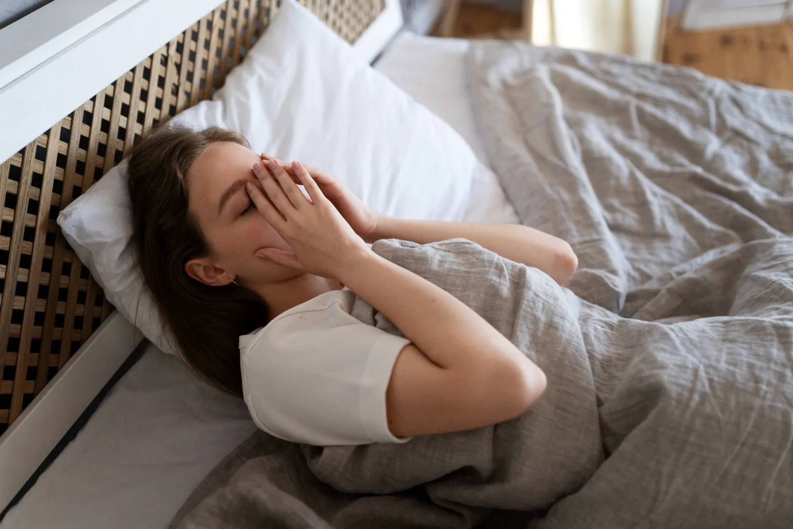 Femme éveillée dans son lit la nuit, évoquant la difficulté à dormir malgré la fatigue